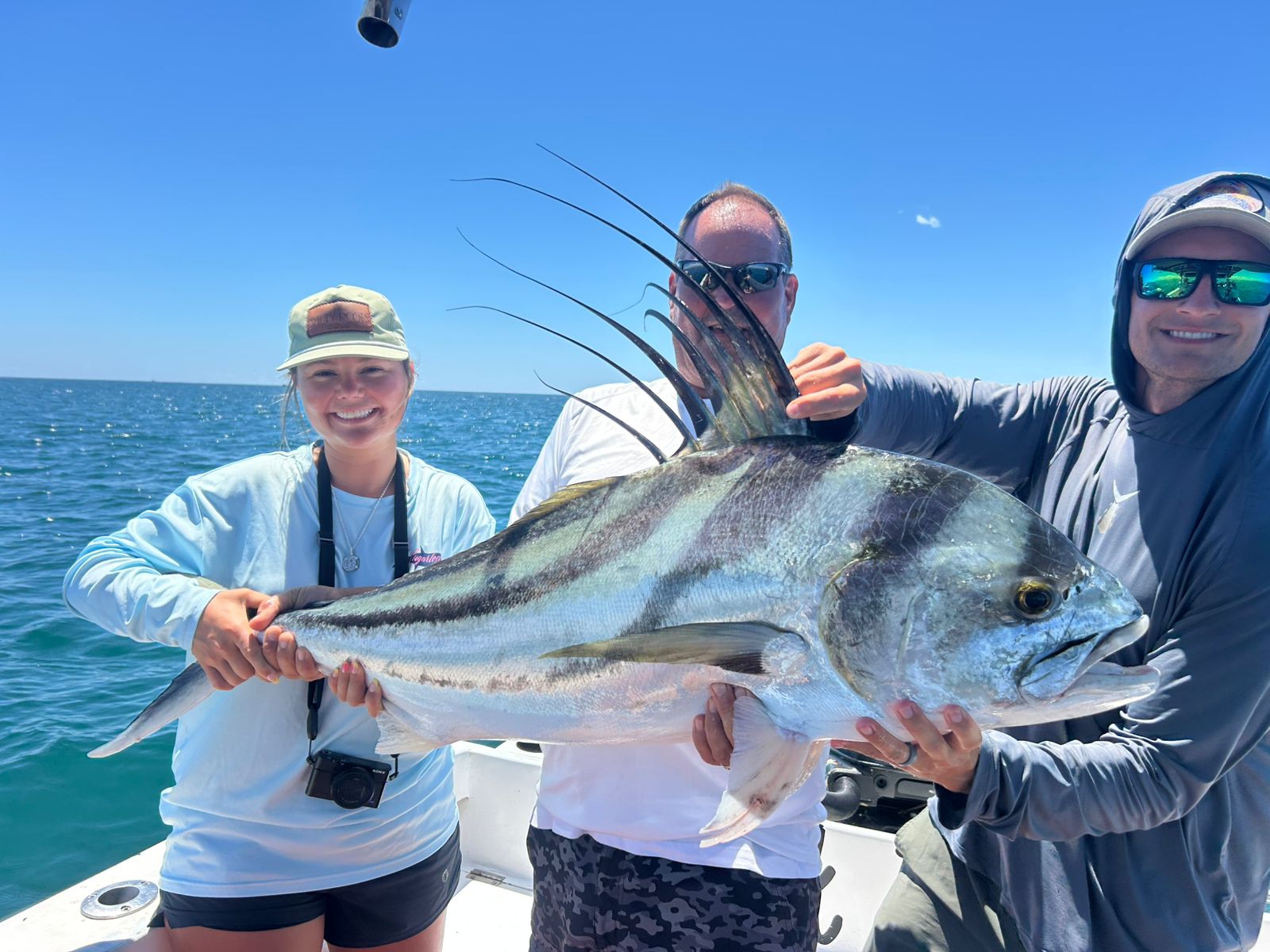 Three people holding a massive roosterfish